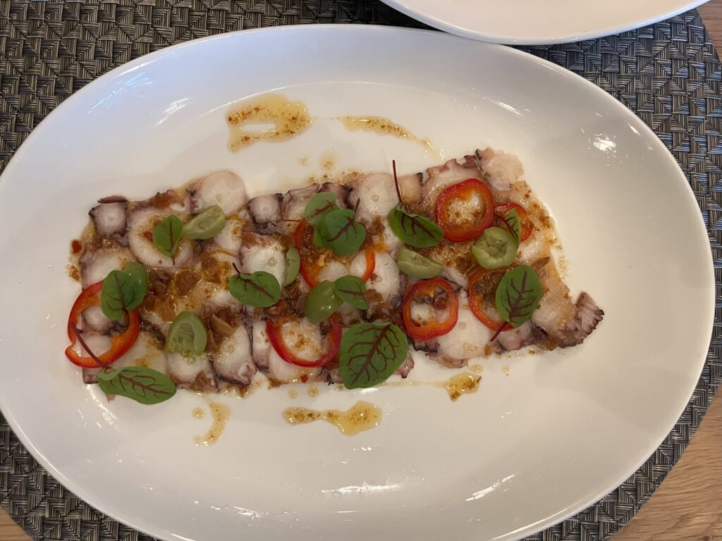 Octopus terrine with micro herbs and jalapenos.